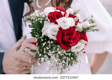 A colorful horizontal wedding photograph, featuring an exquisite close-up of the bride's wedding bouquet. In the background, a close-up of the bride and groom holding hands, showcasing their wedding r