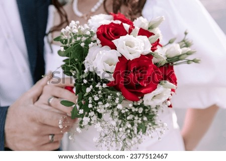 A colorful horizontal wedding photograph, featuring an exquisite close-up of the bride's wedding bouquet. In the background, a close-up of the bride and groom holding hands, showcasing their wedding r