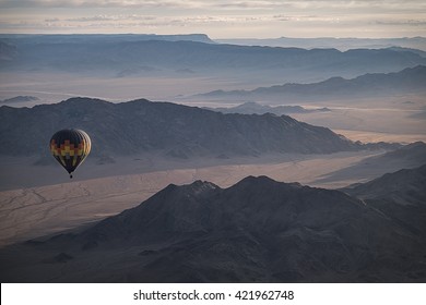 Colorful Hot Air Ballon Flying Over The Mountain Landscape. High Altitude. Early Morning, High Dark Mountains. (Namibia, South Africa)