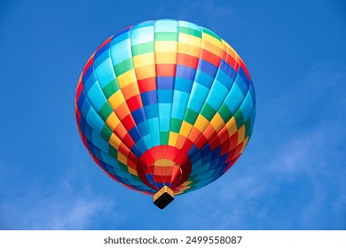 A colorful hot air balloon floating across the blue sky - Powered by Shutterstock