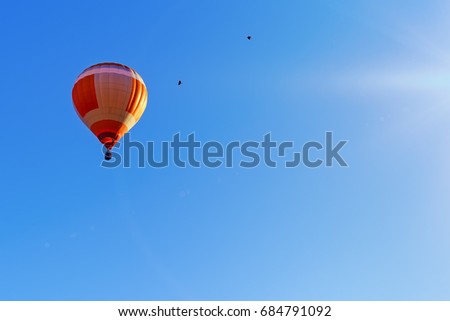 Colorful hot air balloon flying on a beautiful summer morning. The sun's rays illuminate it.