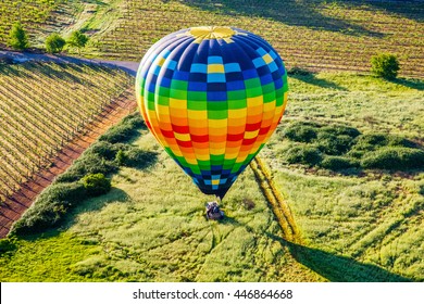 Colorful hot air balloon landing in a field, Napa, California, USA.