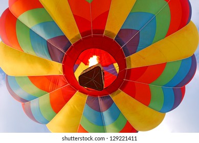 Colorful hot air balloon rising with flame burning.