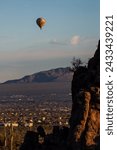 A colorful hot air balloon in the sky above the Sonoran Desert. Early morning adventure in a balloon floating past mountains and saguaro cacti near Tucson, Arizona in Pima County, USA.