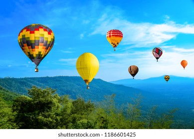 Colorful hot air Balloons  flying above green mountain with  beautiful blue cloudy sky background
