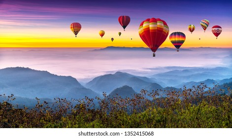 Colorful hot air balloons flying above high mountain at sunrise with beautiful sky background
