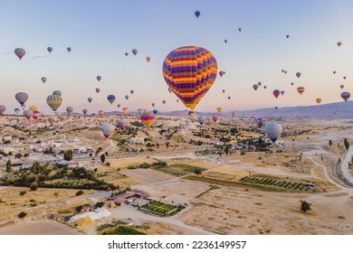 Colorful hot air balloons flying over at fairy chimneys valley in Nevsehir, Goreme, Cappadocia Turkey. Spectacular panoramic drone view of the underground city and ballooning tourism. High quality - Shutterstock ID 2236149957