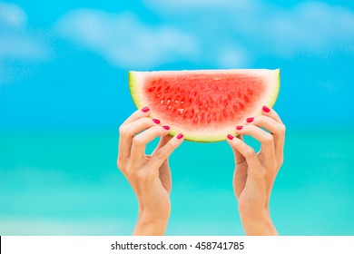 Colorful hot summer holidays.  hand holding slice of watermelon on the beach. 