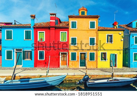 Colorful houses of Burano island. Multicolored buildings on fondamenta embankment of narrow water canal with fishing boats, Venice Province, Veneto Region, Northern Italy. Burano postcard