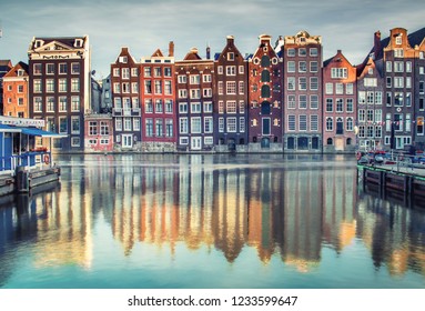 Colorful houses lining Damrak canal in Amsterdam, Netherlands at sunset