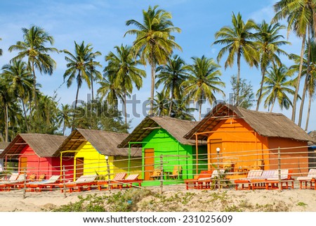 Colorful huts on the sandy beach with palm trees background in Goa, India