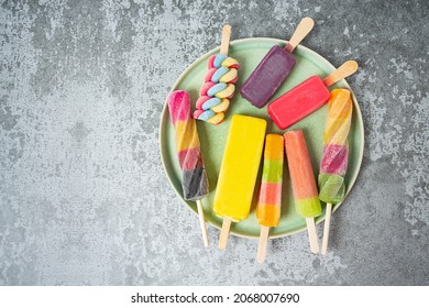 colorful ice cream popsicles on dark backrgound, top view, empty space for your text