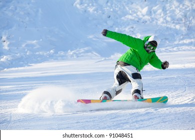 Colorful Image Of Young Snowboarder In Green Jacket Making Powder Turn Trick On A Ski Slope