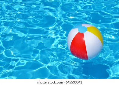 Colorful inflatable ball floating in swimming pool, summer vacation concept