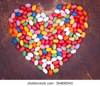 Colorful jelly beans in the shape of a heart on shabby chic surface - Powered by Shutterstock