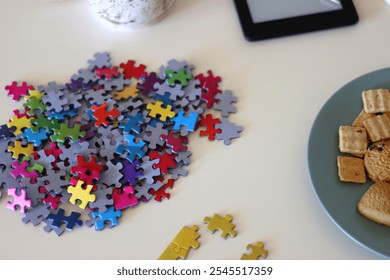 Colorful jigsaw puzzle pieces, books, tablet, glasses, cookies, berries, cup of tea or coffee, glass of juice and lit candles on the table. Hygge in pastel colors. Selective focus. - Powered by Shutterstock