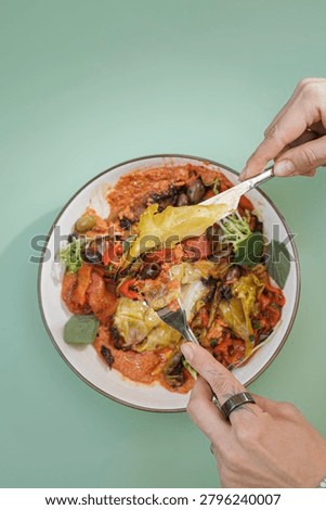 In a colorful kitchen, hands gently pull apart a cheesy vegetable dish, revealing layers of fresh ingredients. The vibrant colors and textures invite savoring every bite with joy.