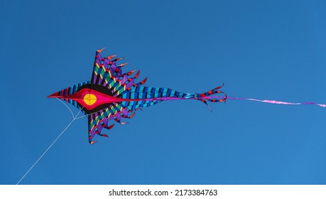 Colorful Kite Isolated Flying In A Blue Sky.
