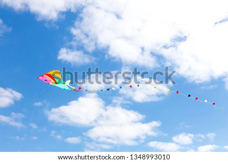 Colorful kite on a blue sky with white clouds.