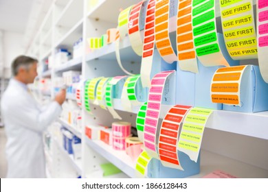 Colorful labels with a male pharmacist looking for medication on a pharmacy shelf in the background.