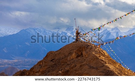 Colorful landscape of Himalaya mountian. Prayer flag blowing in the win with blue mountain background.Snow mountain with cloud in India or Tibet.Panorama landscape of Karakoram.