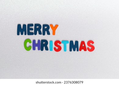 colorful letters with the phrase Merry Christmas on a light background with glitter

