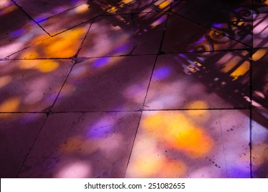 Colorful Light Spots On The Tiled Floor In The Church And Shadow Of Forging Fence. Sunlight Filtered Through The Stained Glass Window.