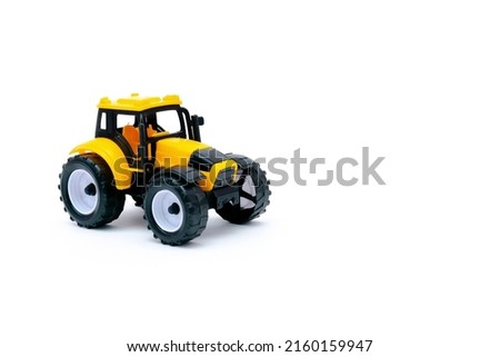 Colorful little mini yellow plastic tractor, truck, lorry, car toy isolated on white background mockup with copy space, toys for children, kids development, playing, childhood fun.