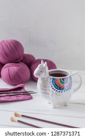 Colorful Llama shaped tea or coffee mug with knitting needles, scissors and wool yarn, hobby postcard concept