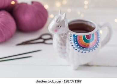 Colorful Llama shaped tea or coffee mug with knitting needles, scissors and wool yarn, hobby postcard concept