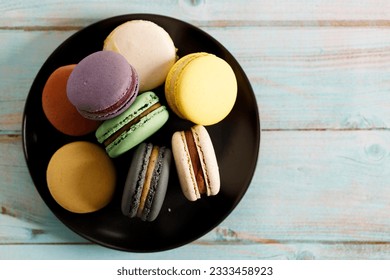 Colorful macaron cookies on black color plate. Sweet French macarons in different colors. Closeup.