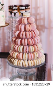 Colorful macarons on pyramid-shaped glass tower stand as part of candy bar sweet table