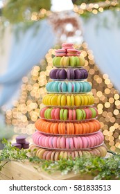 Colorful macarons on pyramid-shaped plastic stand on many visible levels. Cake macarons for wedding with Bokeh Background.