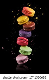 Colorful macaroons stack on black background with crumbs. Food levitation, flying