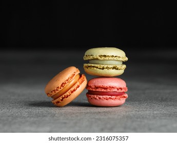 Colorful macaroons stacked in a pile on a grey table, black background - Powered by Shutterstock