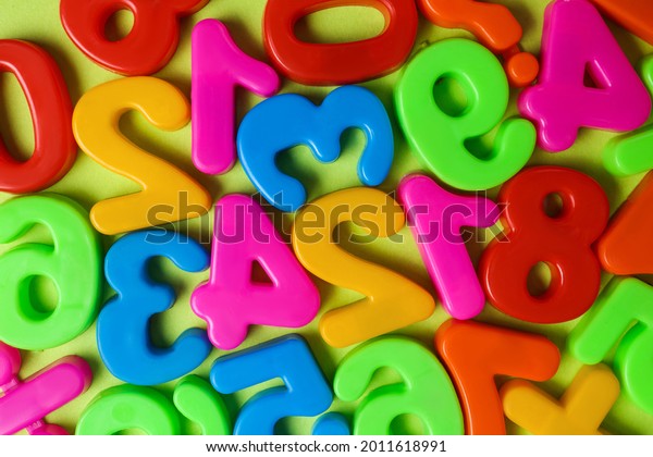 Colorful magnetic numbers on light green background,\
flat lay