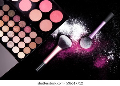 Colorful makeup palette and brush to apply powder. on pure black background. 