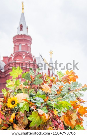 Colorful maple leaves,sunflowers and hawthorn berries. Beautifully designed autumn decor on the Red Square in Moscow. Red brick tower on background.