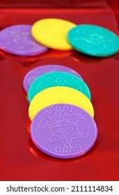 Colorful Mardi Gras Coins Stacked In A Row On Red Metallic Paper.