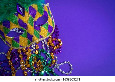 Colorful Mardi Gras mask on purple background with beads