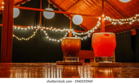 Colorful Margarita Coctail Served In A Glass On The Wooden Board, Drink Served On A Bar Counter In Empty Bar, No People In The Bar With Refreshing Drink Melting On The Bar Counter. 