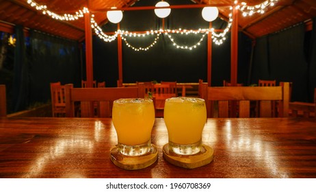 Colorful Margarita Coctail Served In A Glass On The Wooden Board, Drink Served On A Bar Counter In Empty Bar, No People In The Bar With Refreshing Drink Melting On The Bar Counter. 