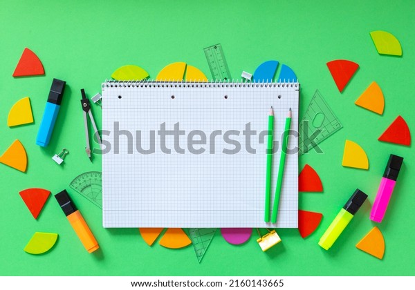 Colorful math fractions, rulers, open notepad on\
a green  background. Interesting, fun math for kids. Education,\
back to school concept