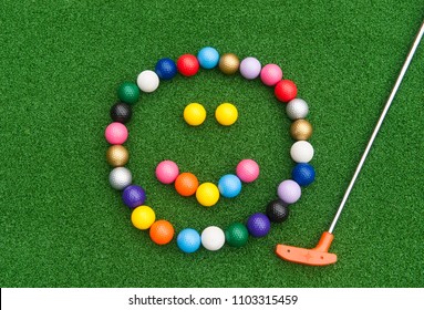 Colorful Mini Golf Ball Happy Face With Orange Putter On Synthetic Grass