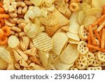 Colorful mix of salty snacks for beer varieties: chips and pretzels, onion rings and crackers. Non-healthy junk food background