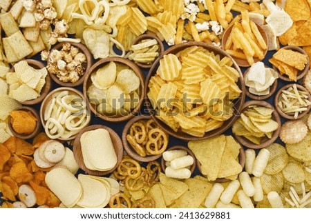 Colorful mix of salty snacks for beer varieties: chips and pretzels, onion rings and crackers. Non-healthy junk food background
