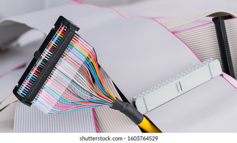 Colorful multi wire bus connector on white ribbon cables background. Internal integrated drive electronics for digital data attachment on floppy, compact or hard disk. Old spare parts. E-waste detail.