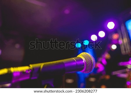 Colorful musical performance: close-up view of microphone on stage with vibrant purple and blue lights in the night