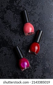 Colorful Nail Polish Bottles On A Black Table. Top View.