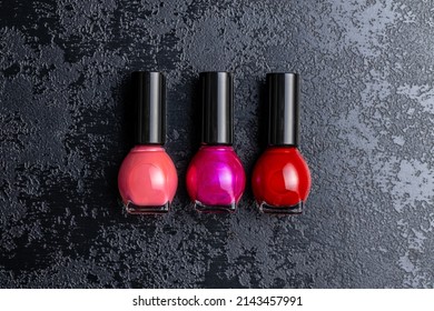 Colorful Nail Polish Bottles On A Black Table. Top View.